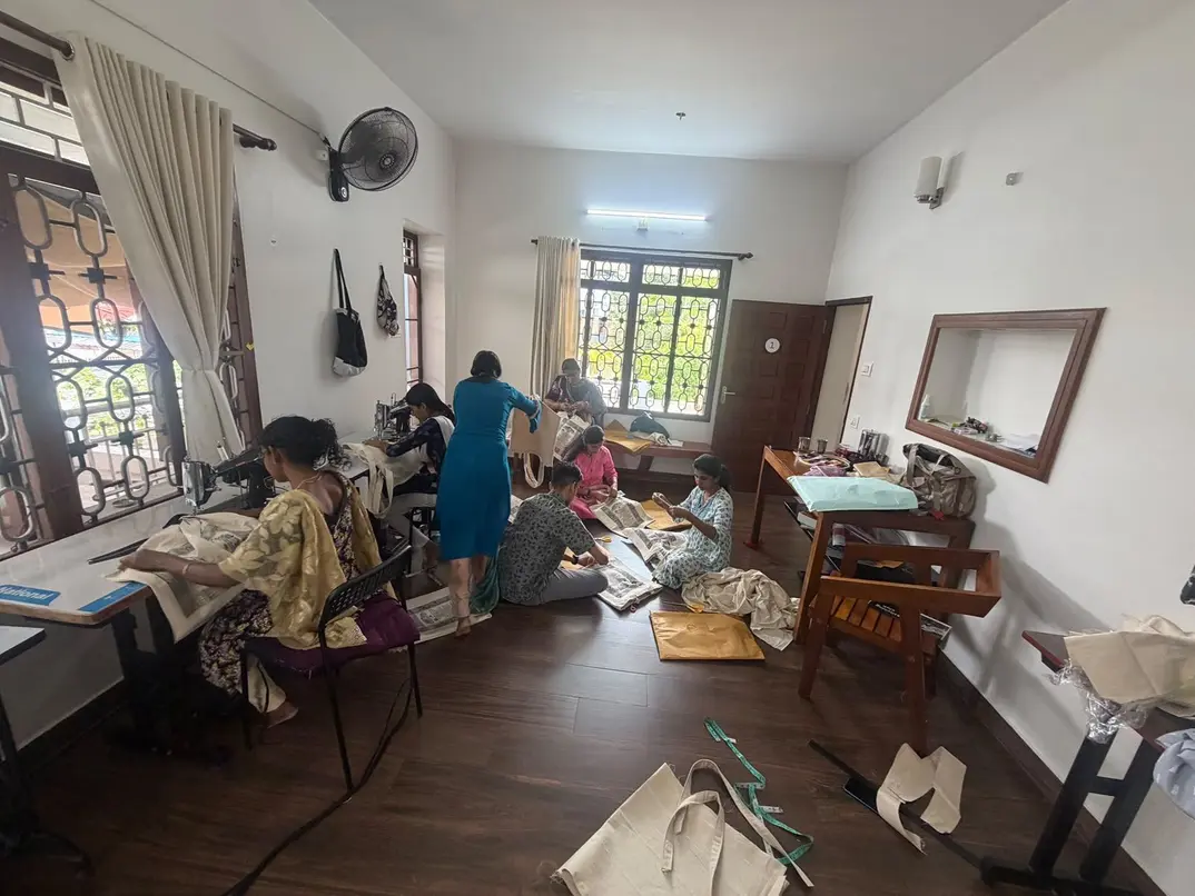 The Stitching Club room at aikyam space, with members cutting, stitching and finishing Constitution Totes